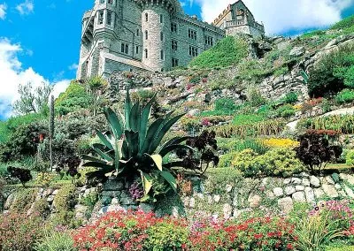 Majestic castle with lush terraced gardens under a vibrant blue sky, showcasing architectural and natural beauty.