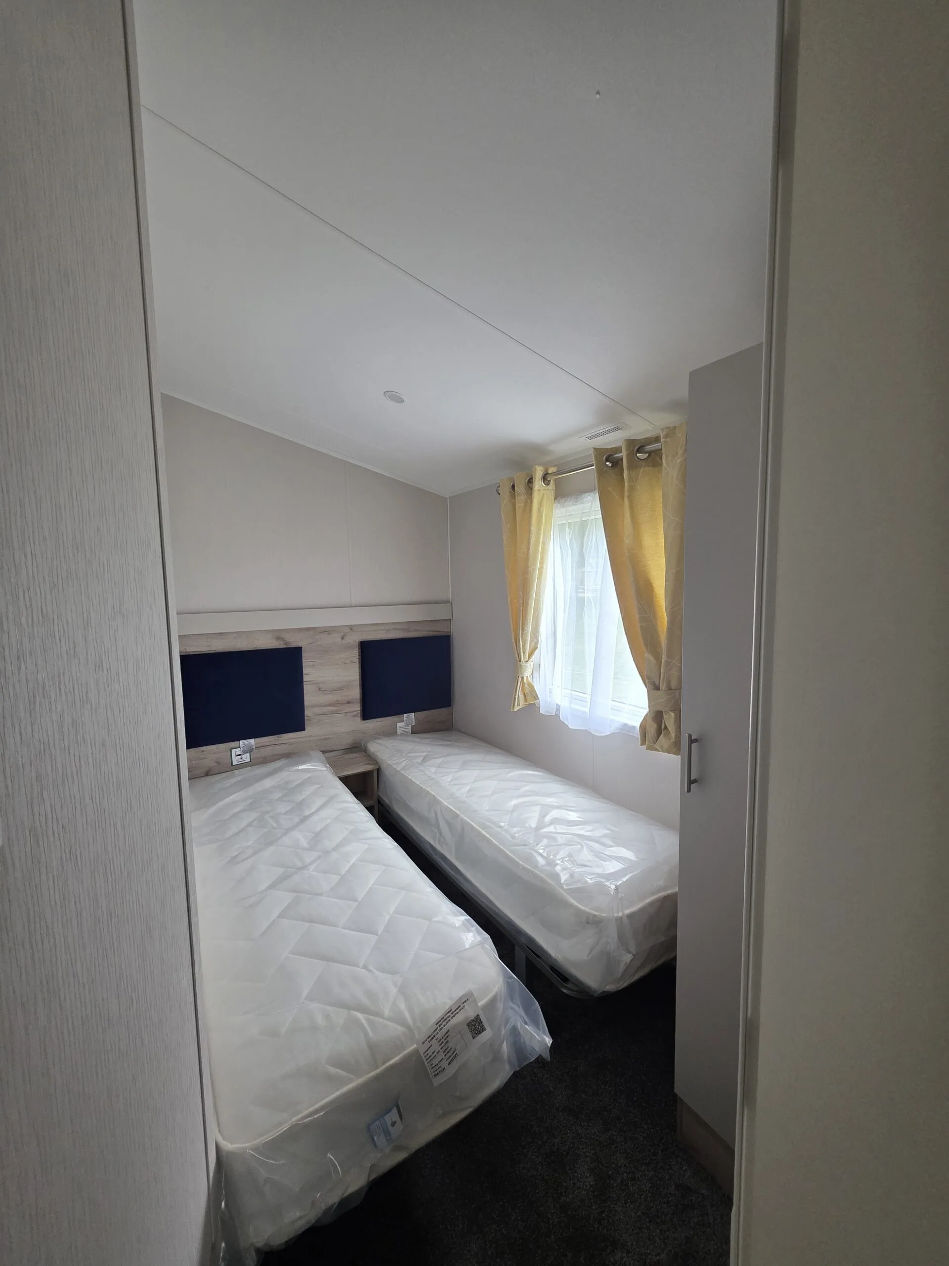 Caravan holiday home twin bedroom with beds made up, Cornwall.