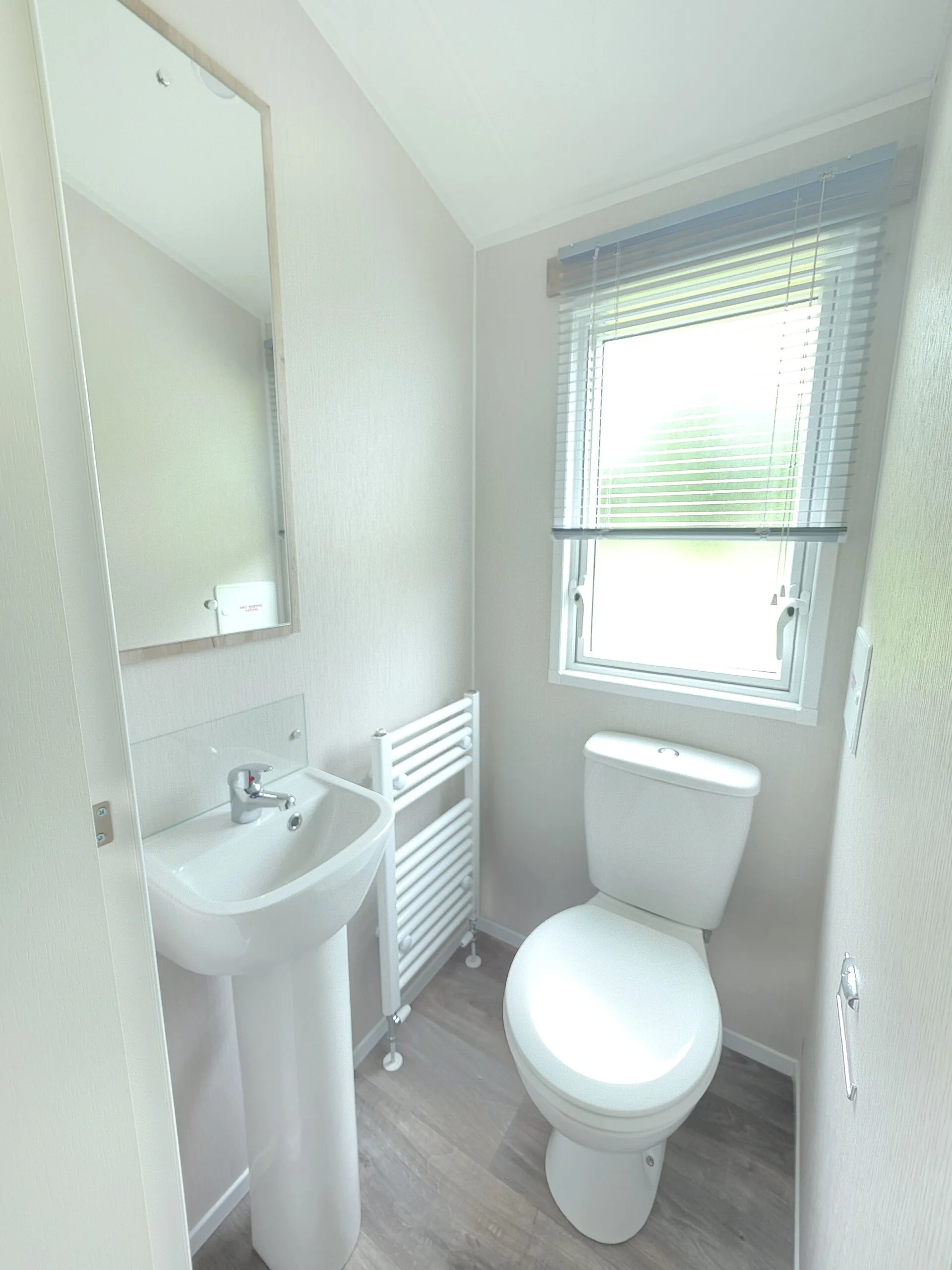 Modern caravan bathroom with toilet, sink, and towel radiator