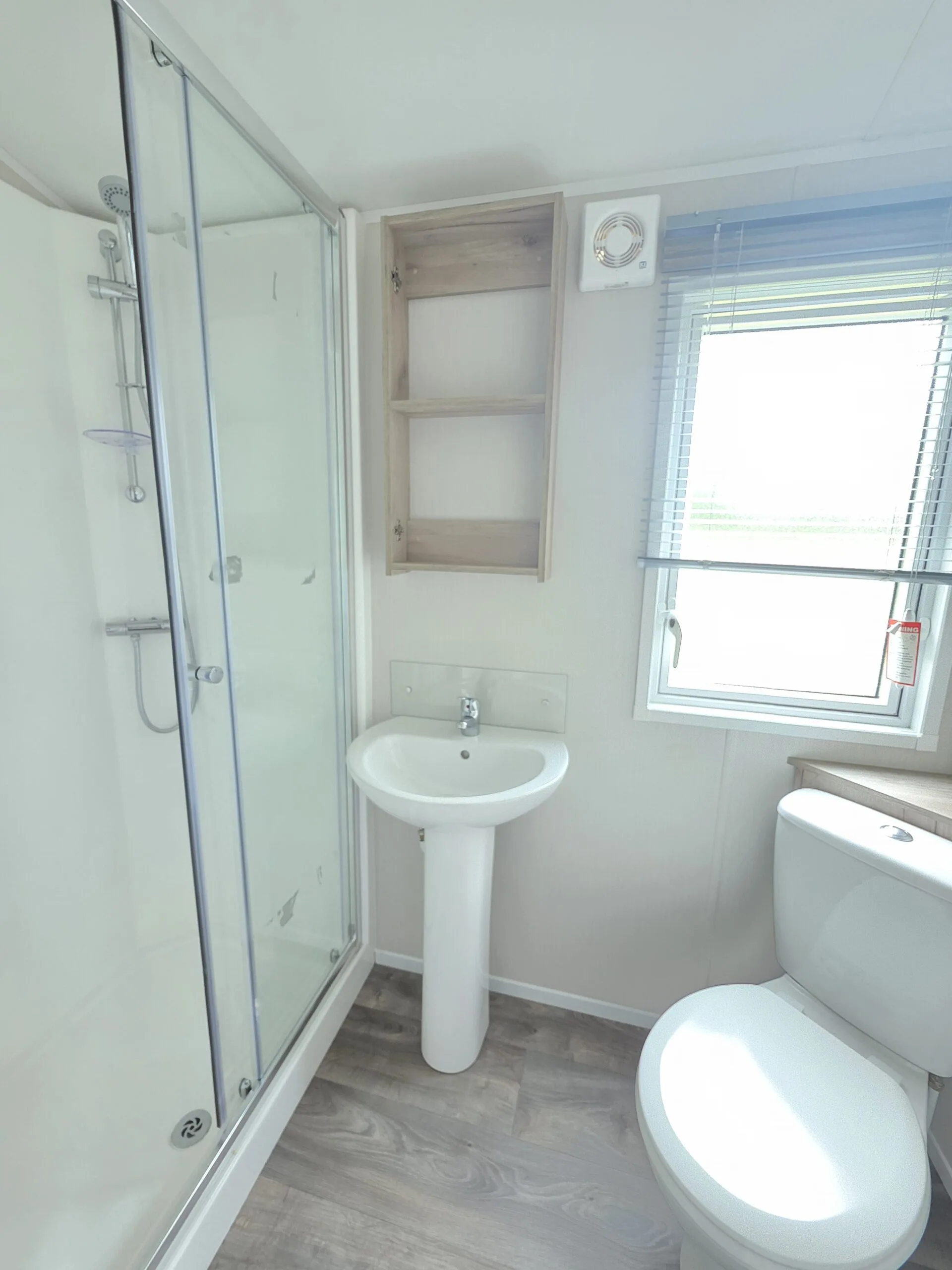 Modern caravan bathroom with shower, sink, and toilet, perfect for Cornwall holidays.