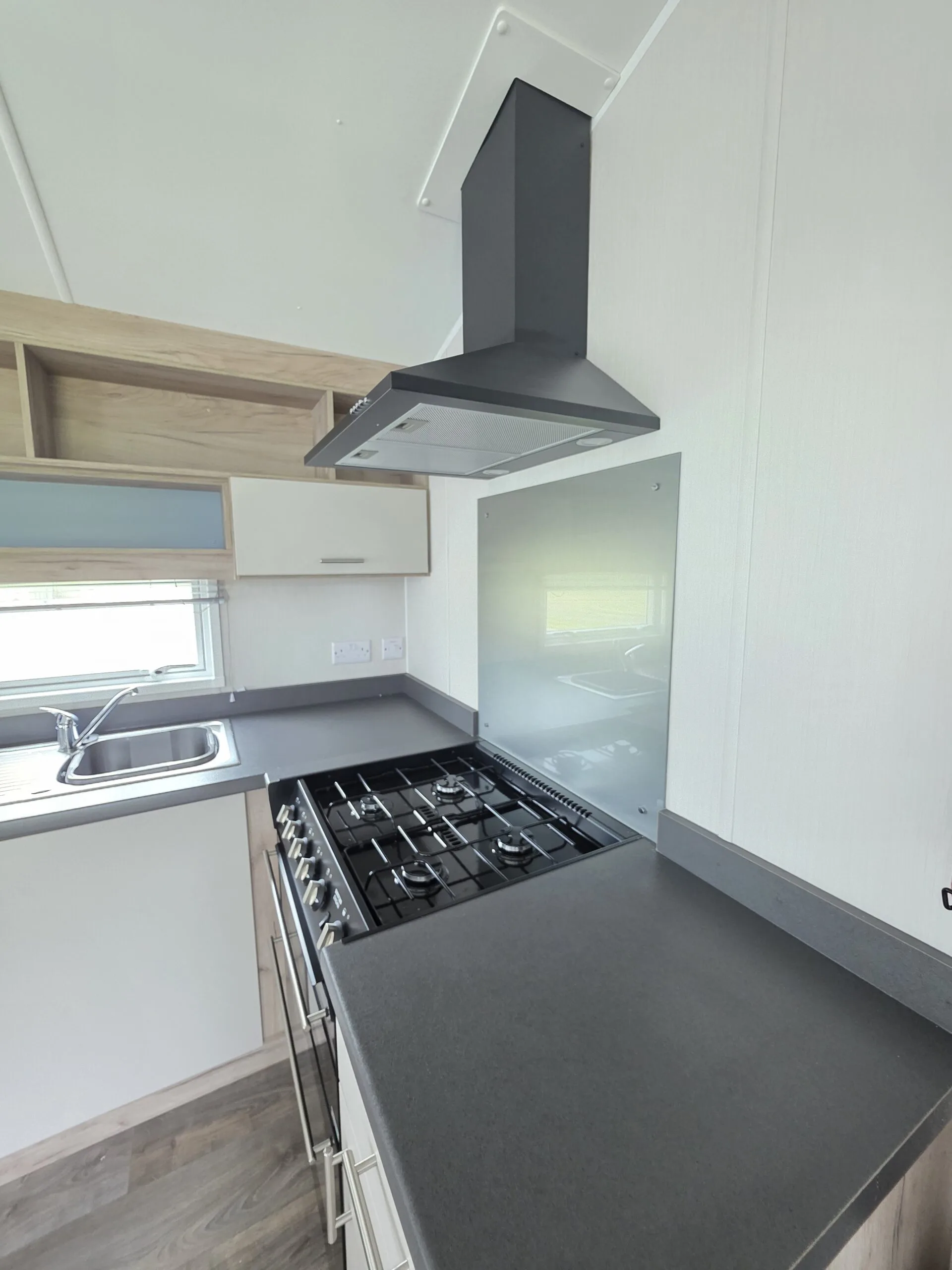 Modern caravan kitchen with gas hob, extractor fan, and sink.