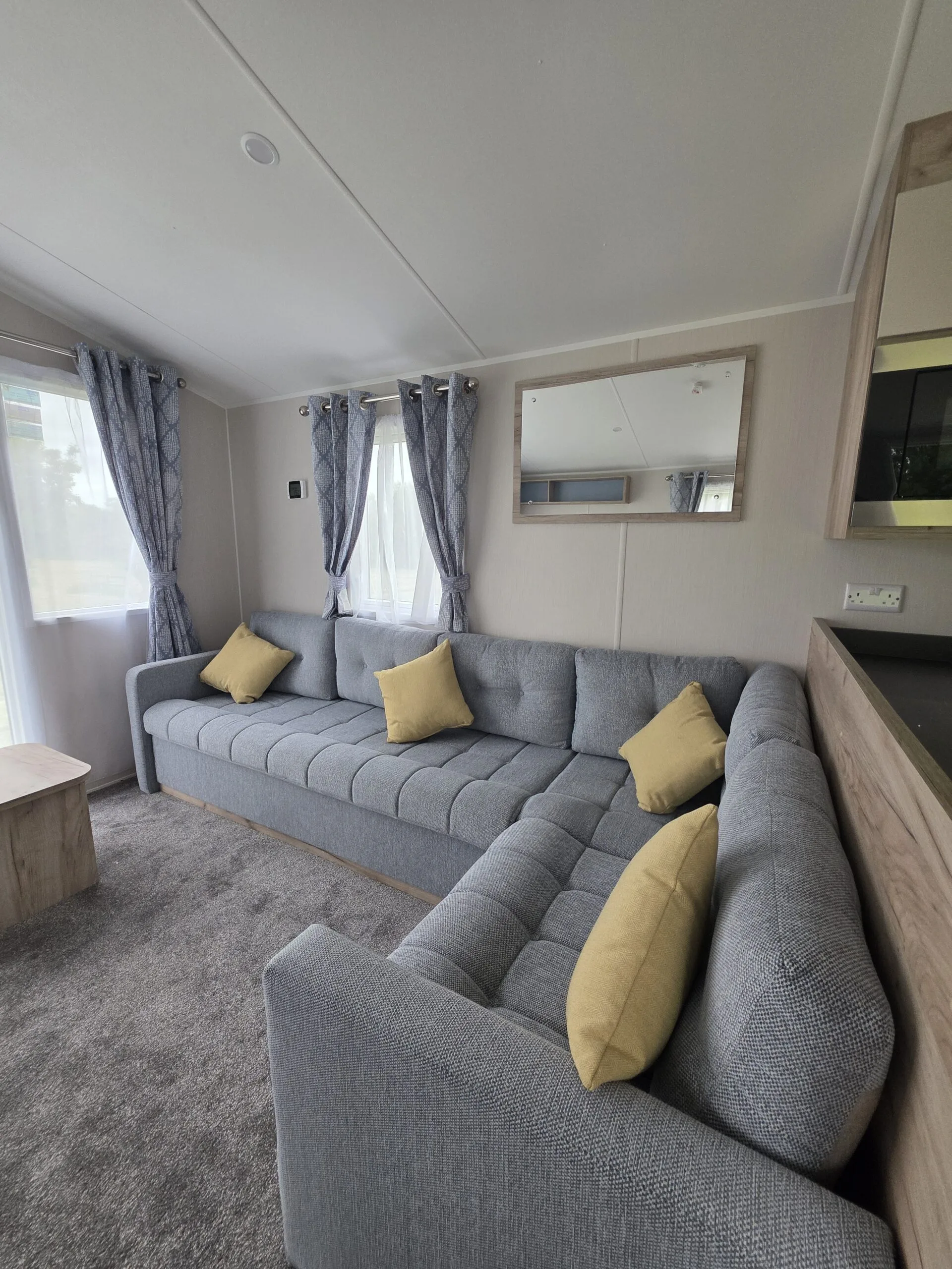 Spacious caravan lounge with L-shaped sofa and yellow cushions