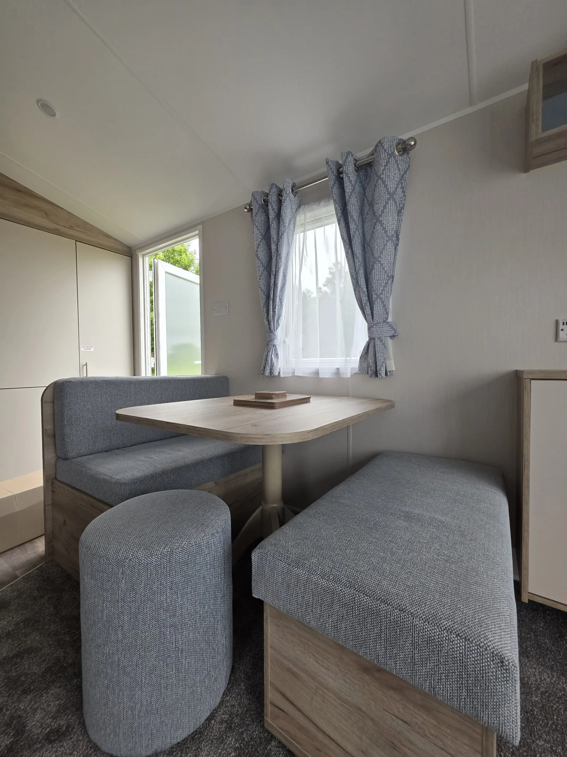 Caravan dining area with U-shaped seating and a table, perfect for holiday homes in Cornwall.