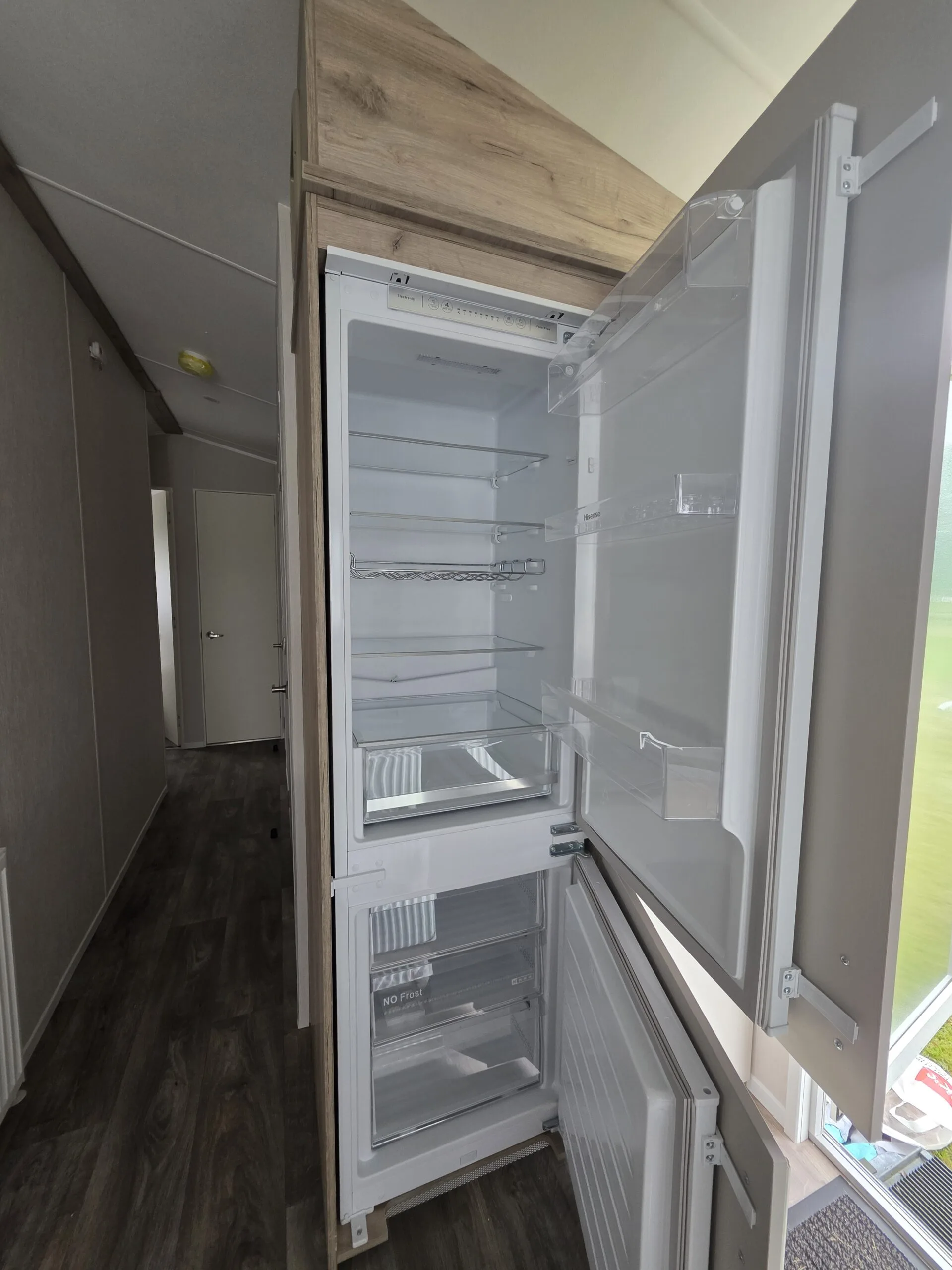 Open caravan fridge freezer with empty shelves and drawers