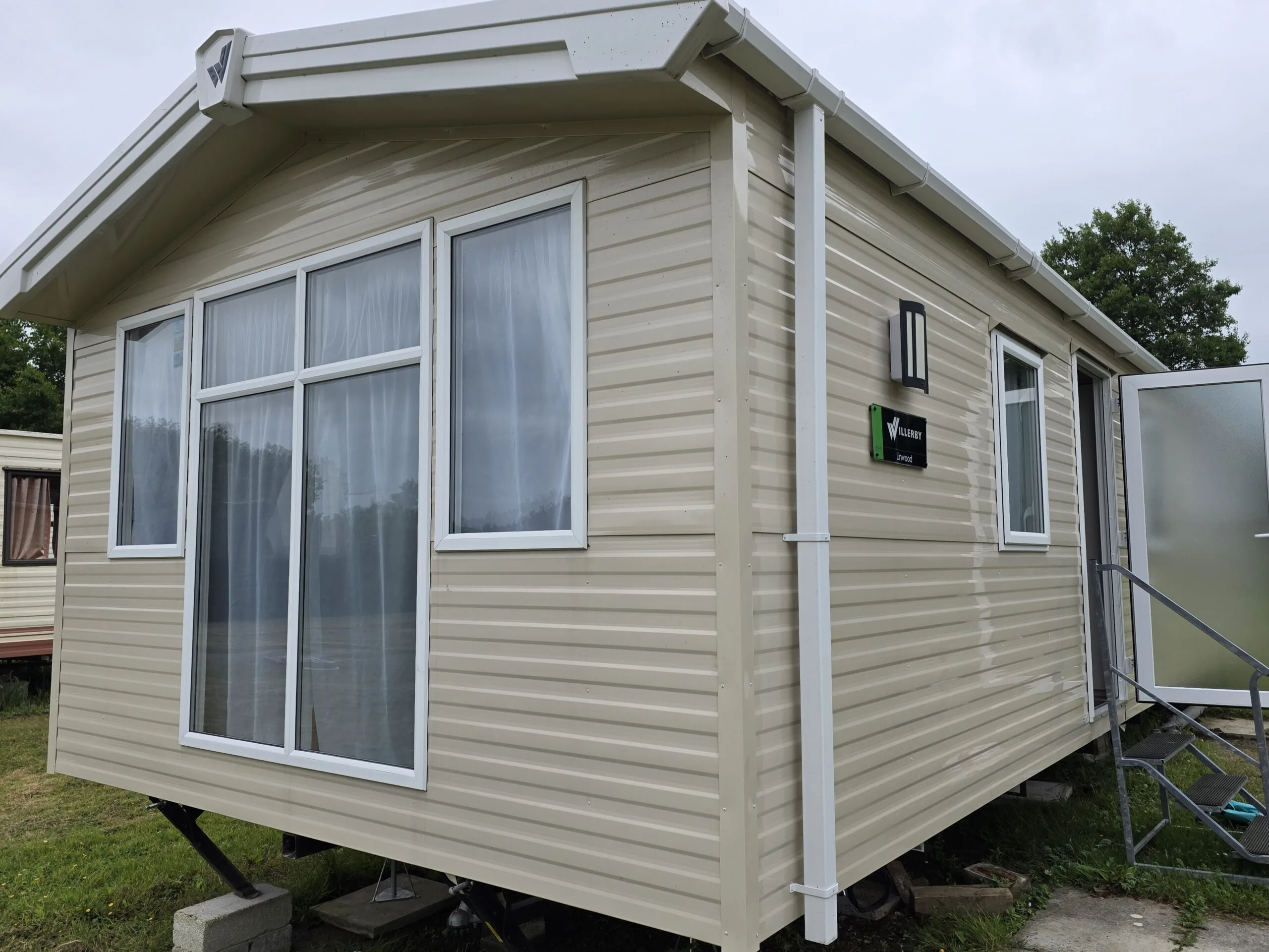 Caravan holiday home in Cornwall with large windows and beige siding.